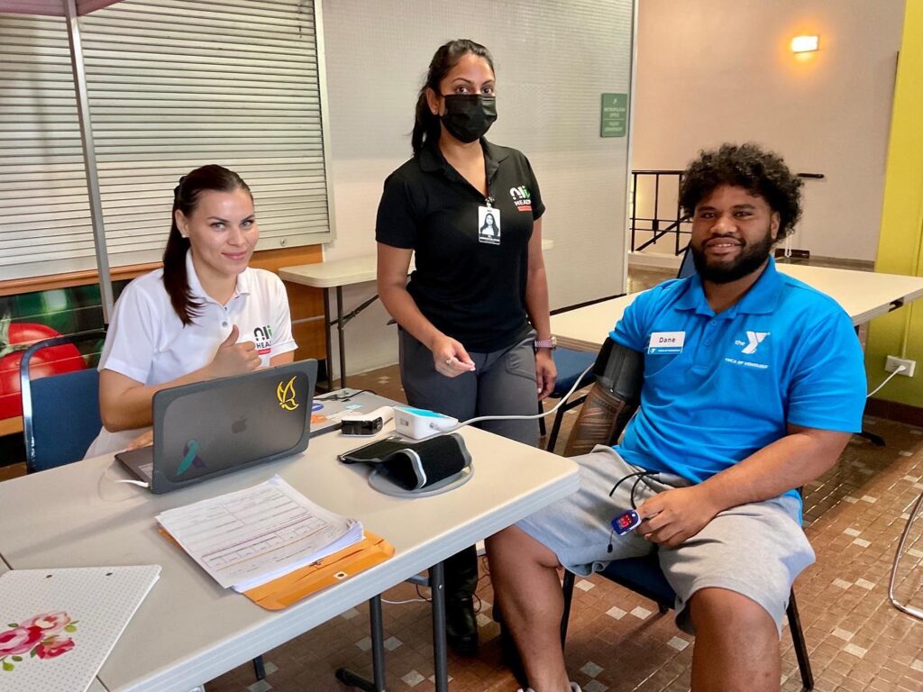 Man receiving a blood pressure check at a community health booth.